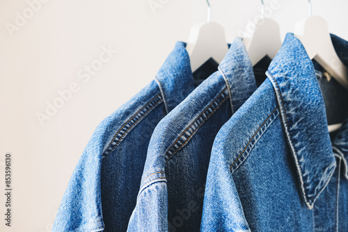 Blue denim jackets on hangers. Different shades of blue jeans color. photo