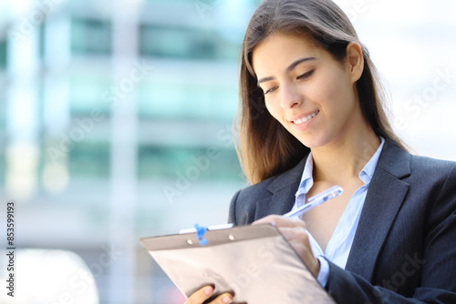 Satisfied businesswoman filling form in the street photo