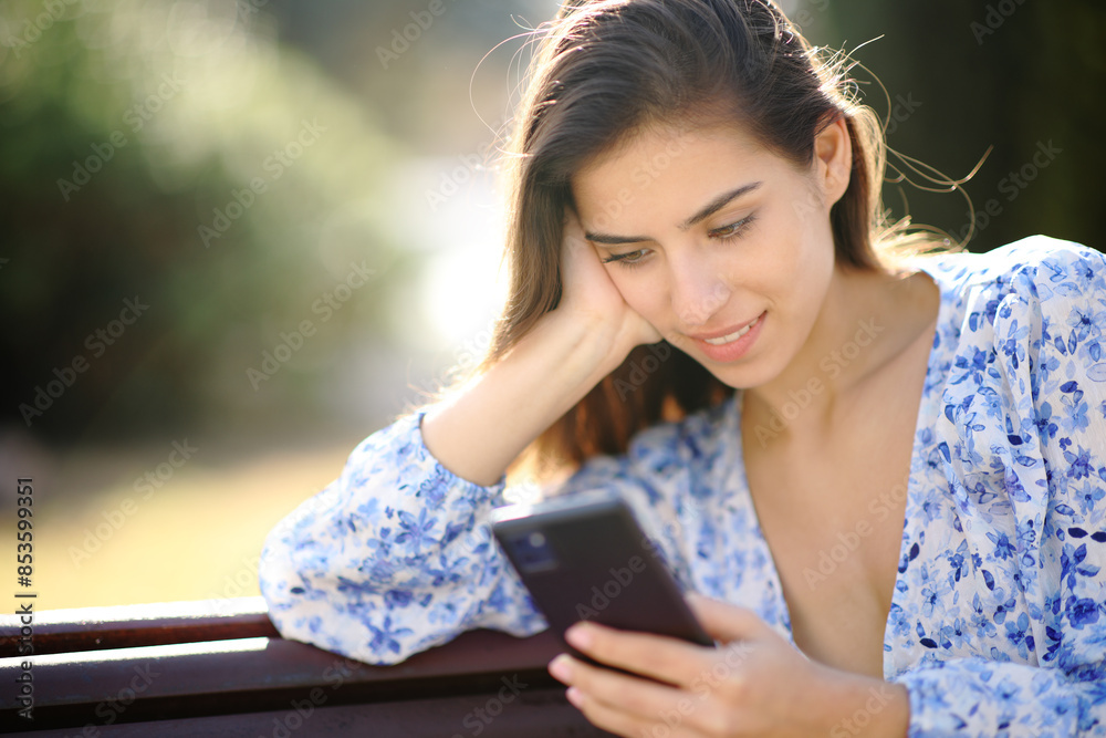 Woman checking phone message in a park Woman checking phone message in a park