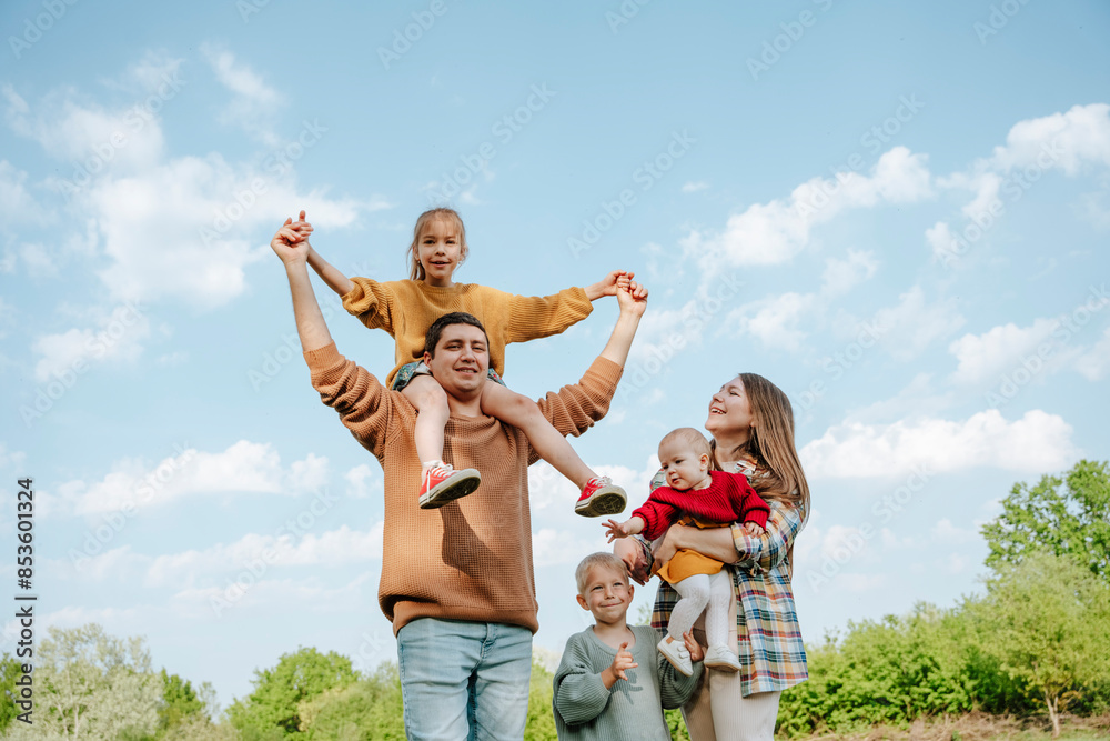 Father carrying daughter on shoulder and standing with family at farm Father carrying daughter on shoulder and standing with family at farm