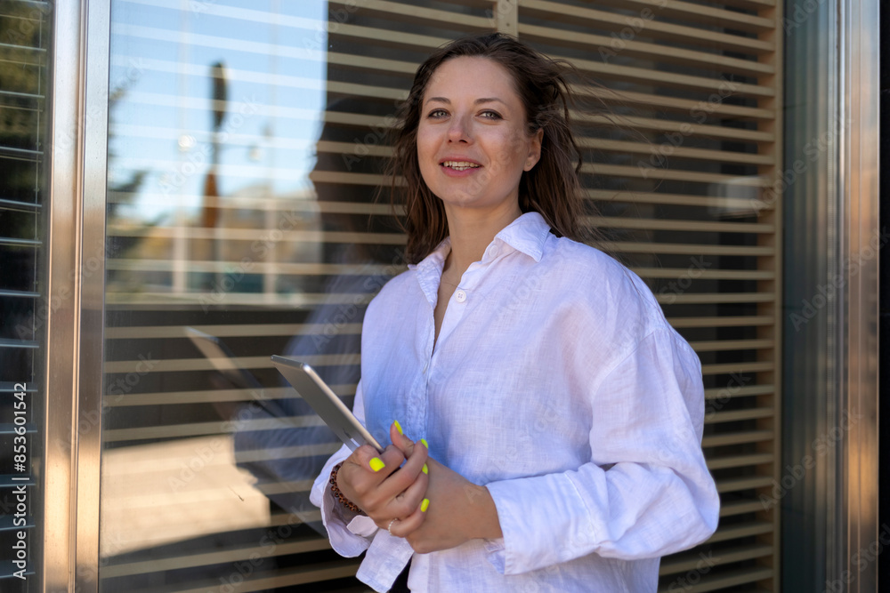 Happy businesswoman standing with tablet PC near glass window Happy businesswoman standing with tablet PC near glass window