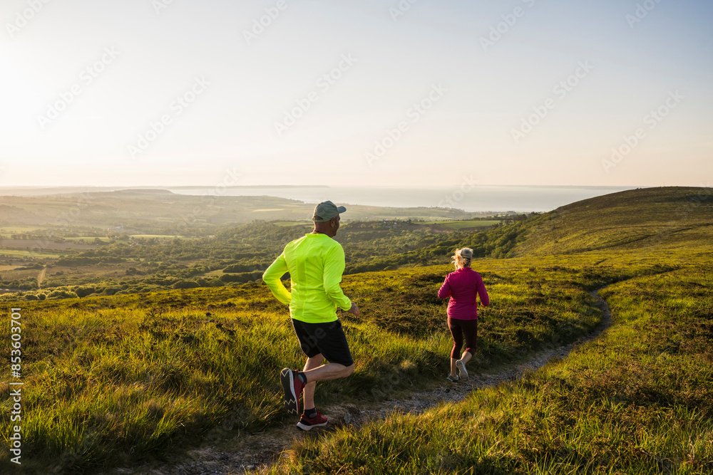 Fit man and woman running on mountain at sunset Fit man and woman running on mountain at sunset