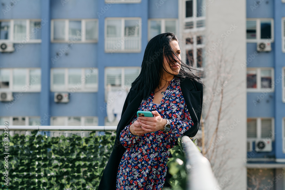 Businesswoman in Black Suit Using Smartphone on Break in Modern Urban Environment. Businesswoman in Black Suit Using Smartphone on Break in Modern Urban Environment.