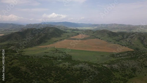 Aerial panorama three harvesting machines cultivates field in summer in Georgia countryside caucasus mountains.Shulaveri village. Seasonal Crops and farming in Europe concept photo