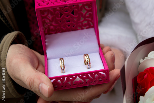 Wedding rings in a pink box in the hands of women
