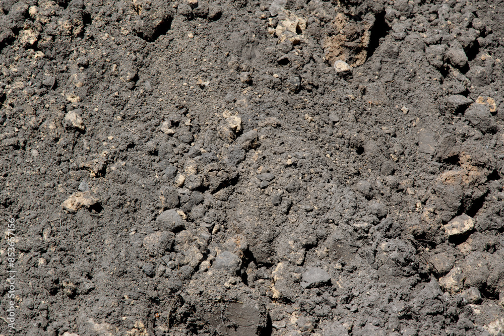 A close-up view of dark soil with small rocks scattered throughout