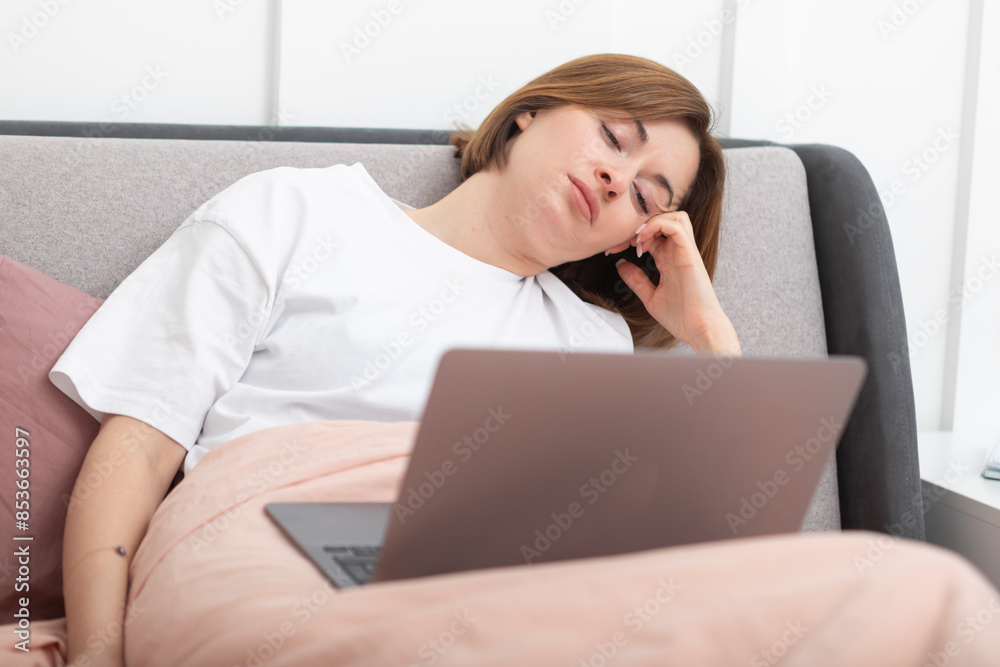 Attractive woman lying in the bed and working on laptop Attractive woman lying in the bed and working on laptop