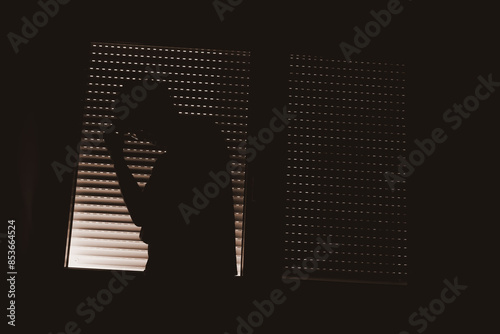 Paranoid personality disorder concept, silhouette of male person by the window with closed shutters