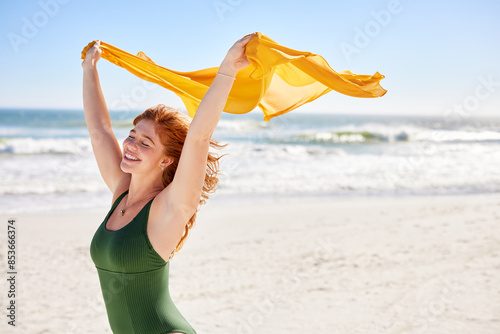 Smiling curvy woman holding yellow scarf at beach photo