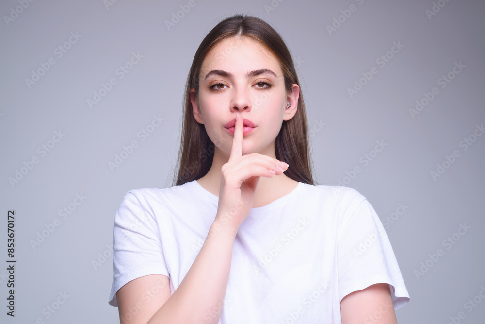 Woman with finger on her lips. Silence gesture. Shhh. Portrait of pretty girl showing silence sign holding forefinger on lips isolated on studio background. Woman showing shhh sign. Woman with finger on her lips. Silence gesture. Shhh. Portrait of pretty girl showing silence sign holding forefinger on lips isolated on studio background. Woman showing shhh sign.