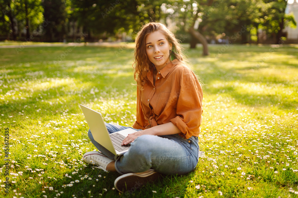 Young woman sits in park communicating by video call. Girl speaking looking at laptop computer, online conference distance office chat, virtual training. Freelance work. Young woman sits in park communicating by video call. Girl speaking looking at laptop computer, online conference distance office chat, virtual training. Freelance work.