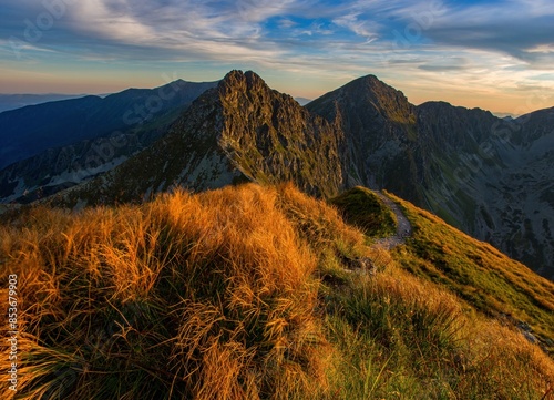 Mountain trail leading along the mountain ridge of beautiful mountains with autumn grass and colorful sky. Western Tatras, High Tatras, Slovakia, Poland. Discovering hiking in a colorful autumn. photo