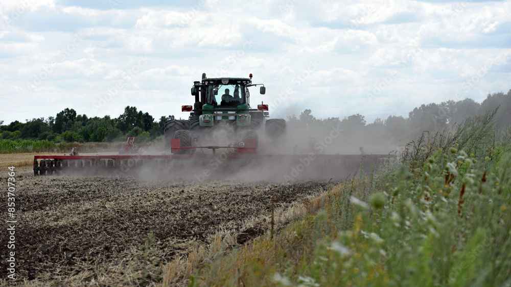 Fototapeta premium Kyiv, Ukraine. tractor in a field, tractor with a plow on an agricultural field. big green tractor working in the field, soil preparation, harvesting, business, agriculture.