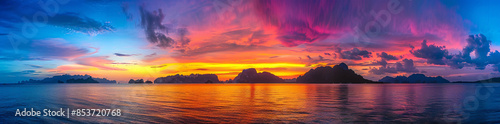 panoramic view of colorful sunset over calm sea lake with mountain range background


