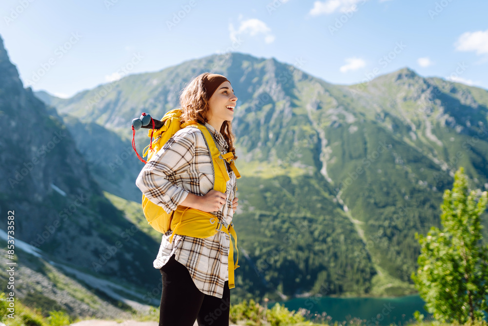 Naklejka premium Young female traveler enjoys beautiful nature while standing on top of the hill. Travel, adventure. Concept of an active lifestyle.
