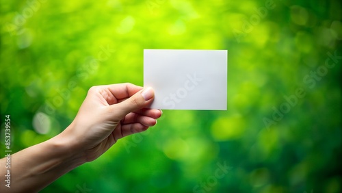 hand holds a white paper on the green background