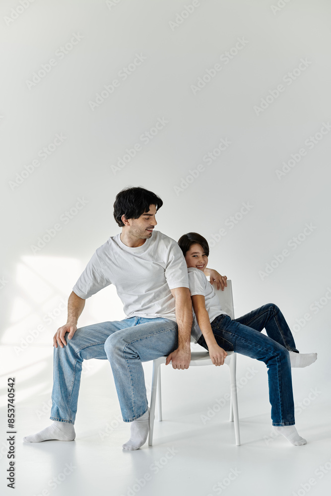 A father and son share a playful moment, sitting on a white chair in a bright room. A father and son share a playful moment, sitting on a white chair in a bright room.