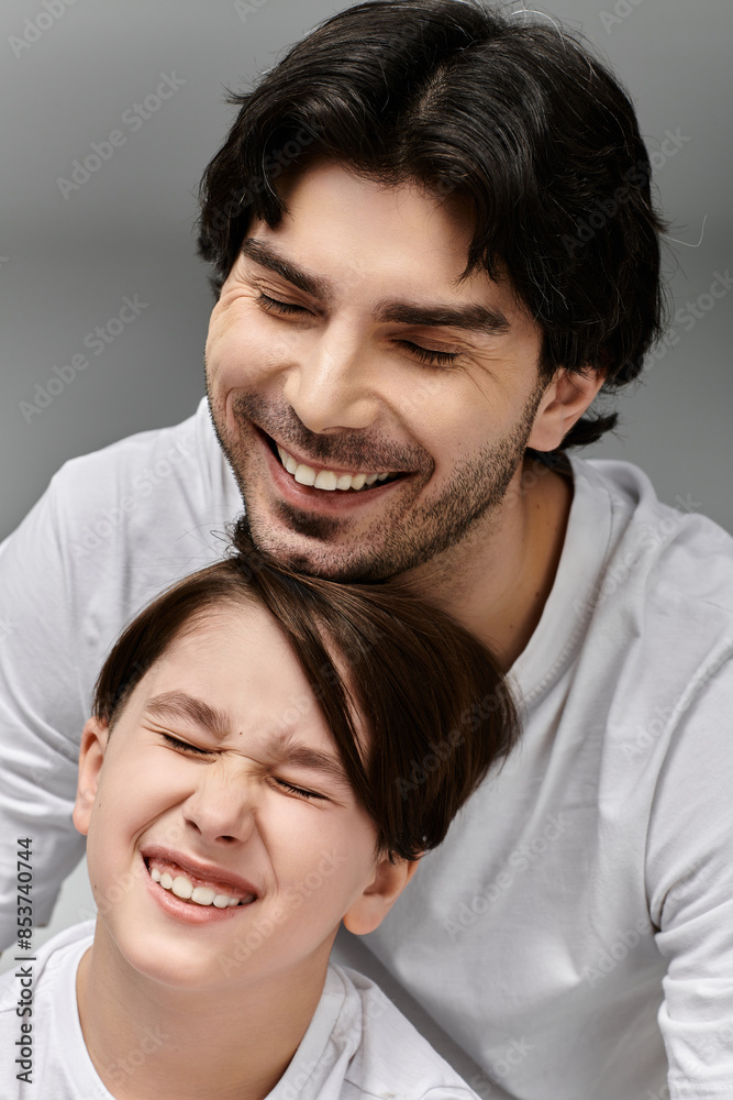 A father and son share a joyful moment, both laughing heartily.