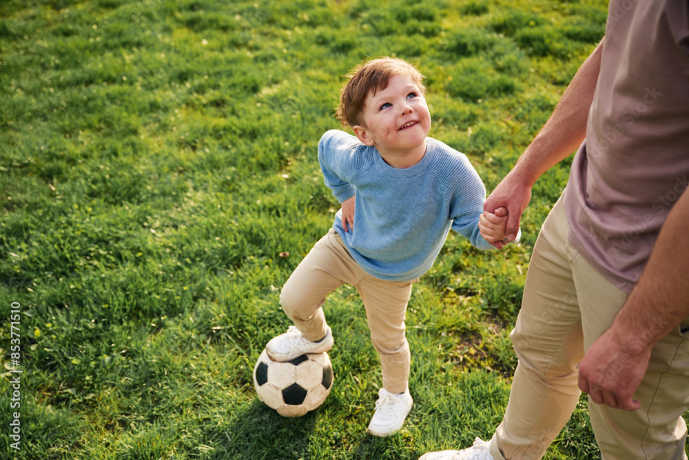 Game of soccer. With ball. Happy father with son are having fun on the field at summertime Game of soccer. With ball. Happy father with son are having fun on the field at summertime