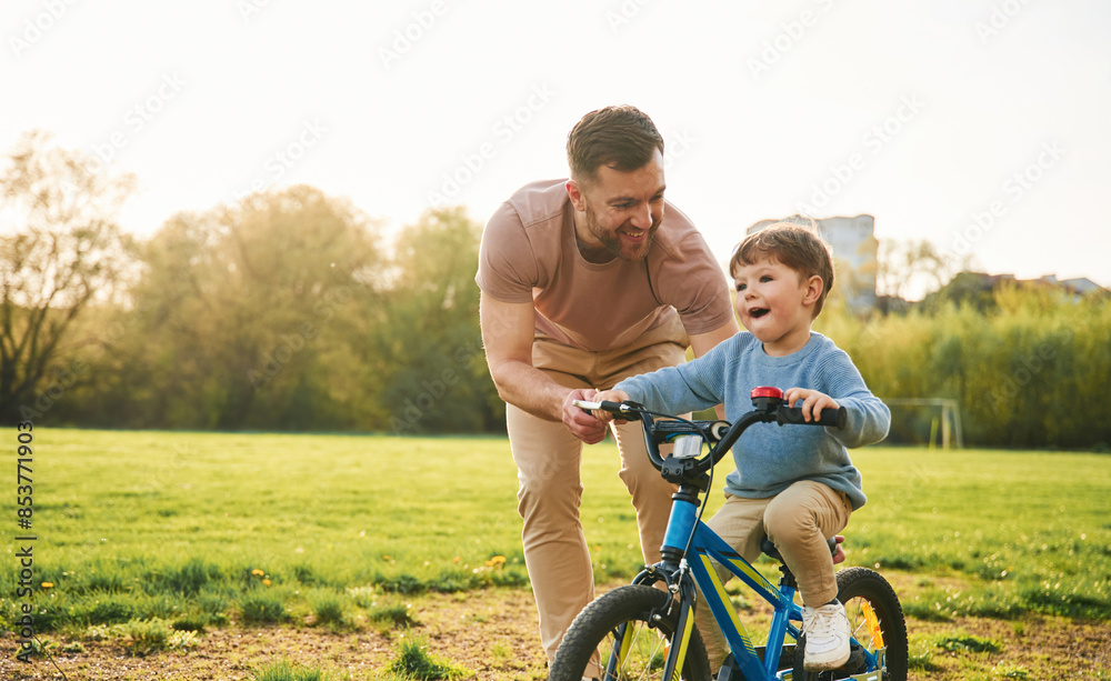With bicycle, having fun. Happy father with son are on the field at summertime With bicycle, having fun. Happy father with son are on the field at summertime