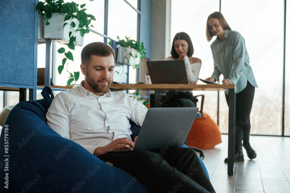 Comfortable bean bag. With laptop. People are working in the office Comfortable bean bag. With laptop. People are working in the office