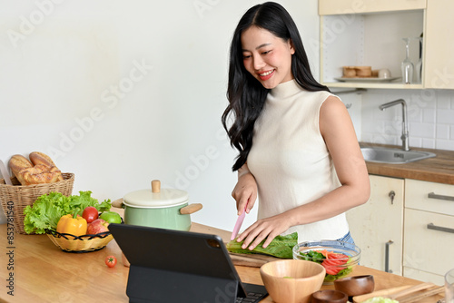 Beautiful woman searching recipe on tablet while cooking in kitchen