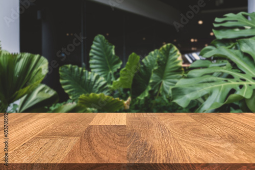 Empty wooden in front of blurred background of  the glass building and the beautiful atmosphere outside the restaurant and cafe decorated with a large pond and green trees give a feeling of freshness.