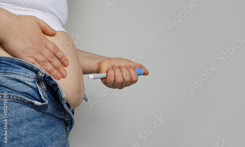 Female person making Injection in her Stomach. Semaglutide or Insulin Injection pen Diabetes Drug Being Used For Weight Loss on white background with copy space