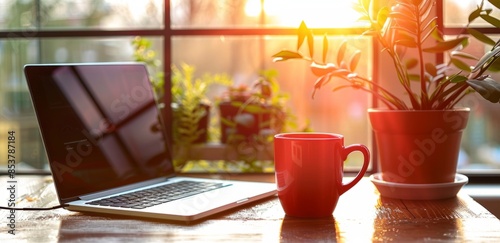 a laptop and coffee mug on an office desk, with natural light streaming in through the window.