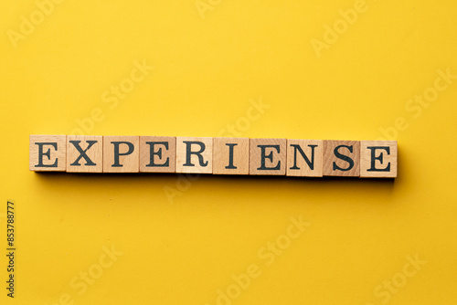 a yellow warm background without shadows wooden cubes with black letters laid out word experiense photo