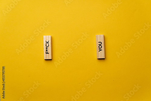 a yellow warm background without shadows wooden cubes with black letters laid out word fuck you photo