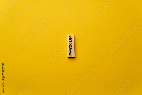 a yellow warm background without shadows wooden cubes with black letters laid out word fuck up