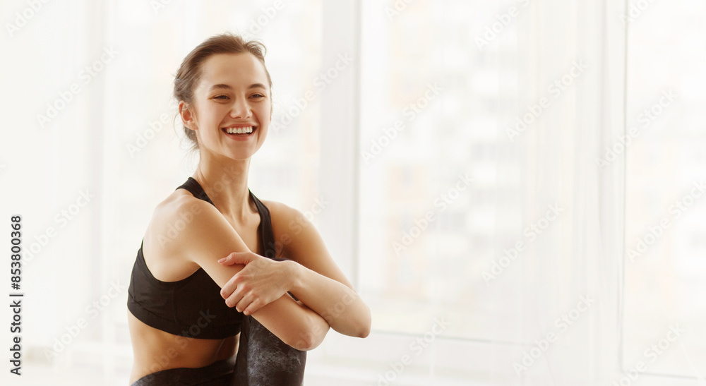 A woman wearing a black sports bra is smiling in the picture. She appears confident and happy as she poses for the camera, showcasing her athletic physique. A woman wearing a black sports bra is smiling in the picture. She appears confident and happy as she poses for the camera, showcasing her athletic physique.