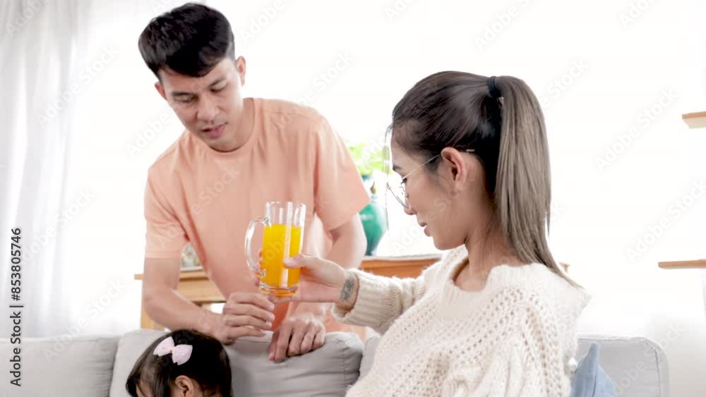 Happy family lifestyle concept, Asian father take care pregnant woman by giving a glass of orange juice, husband and belly wife talking and smiling while cute daughter girl watching playing smartphone Happy family lifestyle concept, Asian father take care pregnant woman by giving a glass of orange juice, husband and belly wife talking and smiling while cute daughter girl watching playing smartphone