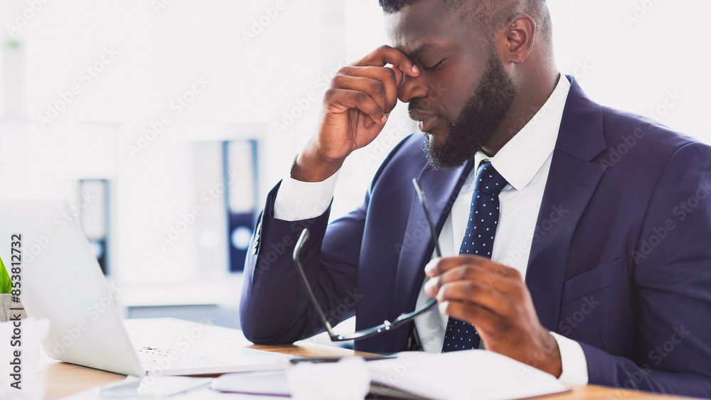 Problems at work. Upset african american businessman massaging his nose bridge holding glasses in hand, copy space Problems at work. Upset african american businessman massaging his nose bridge holding glasses in hand, copy space