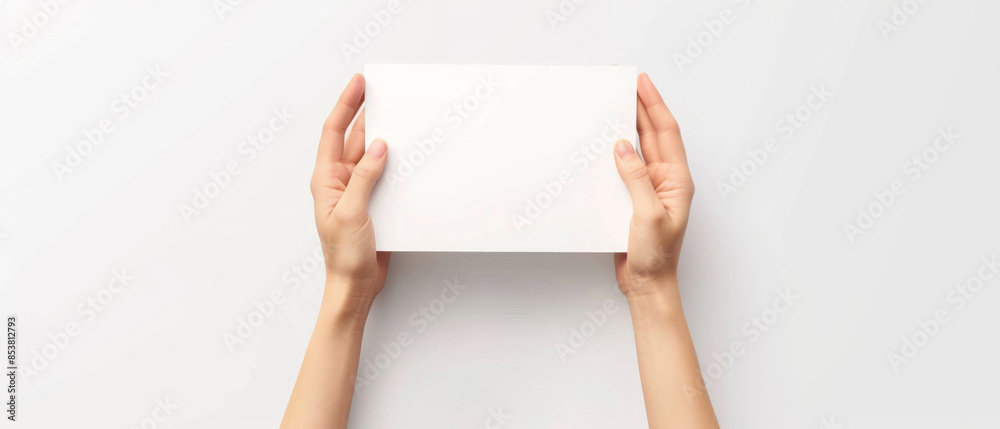 Pair of hands holding a square, blank white paper against a plain background, ready for creativity or message. Pair of hands holding a square, blank white paper against a plain background, ready for creativity or message.