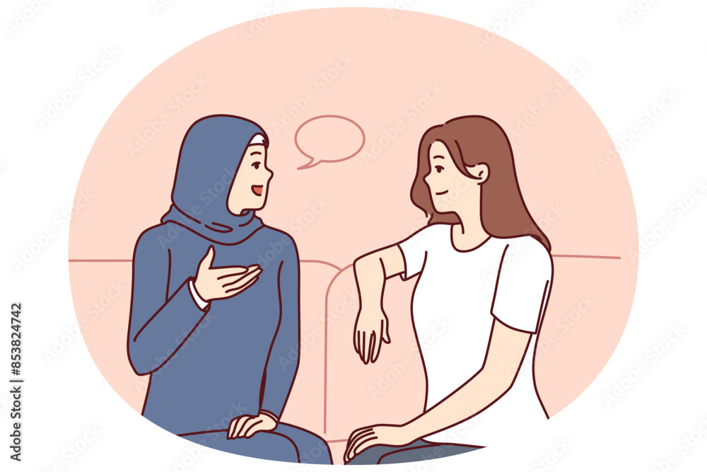 Girls from different ethnicities are talking sitting on couch demonstrating tolerance and lack of cultural prejudice. Woman in muslim clothes is talking to girlfriend of european appearance Girls from different ethnicities are talking sitting on couch demonstrating tolerance and lack of cultural prejudice. Woman in muslim clothes is talking to girlfriend of european appearance