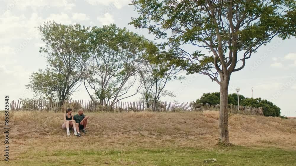 Young athletic couple relaxing in the park in summer sitting on the grass Young athletic couple relaxing in the park in summer sitting on the grass