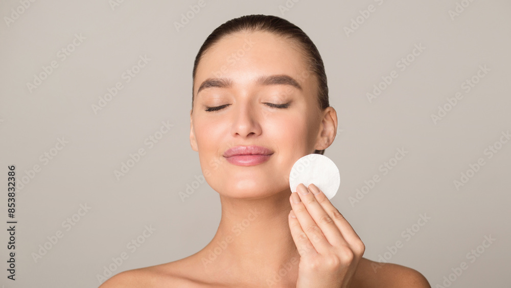 A woman is applying a facial cleanser to her face, using gentle circular motions to cleanse and exfoliate her skin. Her eyes are closed, focusing on the cleansing process. A woman is applying a facial cleanser to her face, using gentle circular motions to cleanse and exfoliate her skin. Her eyes are closed, focusing on the cleansing process.