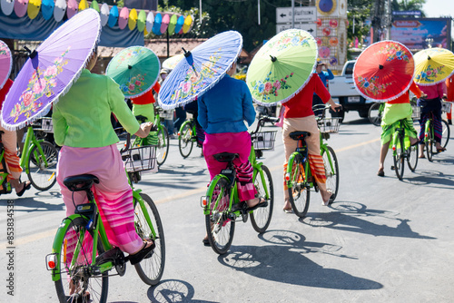 women holding beautiful umbrellas and cycling Performances at the Bo Sang Umbrella Festival, Chiang Mai, Thailand.