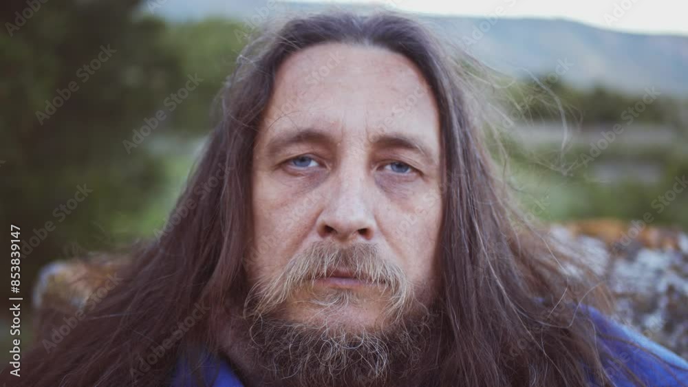 Close-up portrait of a man with a beard and long hair in a medieval knight costume against a background of wild nature. The look of a tired and falling asleep man Close-up portrait of a man with a beard and long hair in a medieval knight costume against a background of wild nature. The look of a tired and falling asleep man