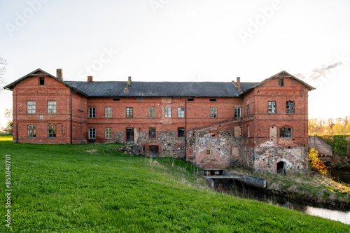 An old red brick mill building in a village on the river bank © ako-photography