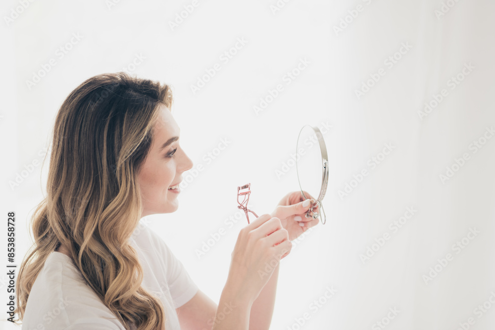 Photo of attractive positive girl look mirror using eye lashes in white bed room indoors Photo of attractive positive girl look mirror using eye lashes in white bed room indoors