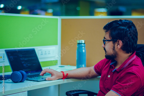 Foto Young man working on his laptop in a modern office.