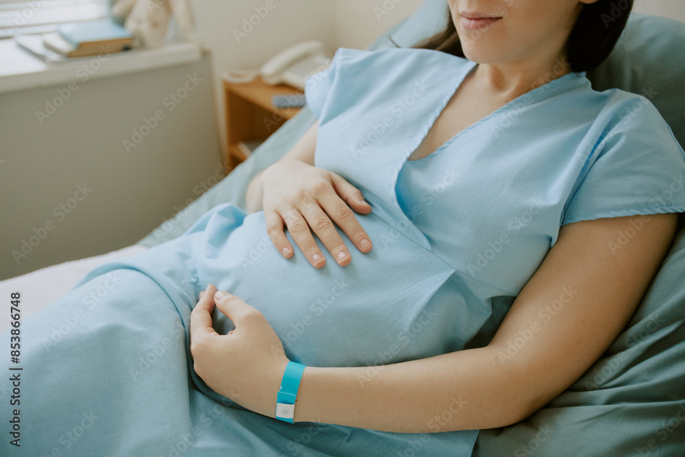 Obraz premium Pregnant woman lying on hospital bed and touching her tummy while she having contractions