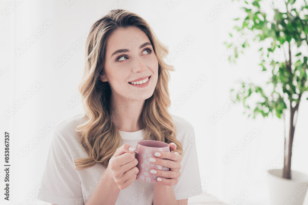Photo of positive girl hold hot coffee cup feel dreamy look in day light room interior Photo of positive girl hold hot coffee cup feel dreamy look in day light room interior