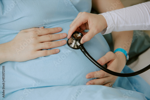 Foto Medium close up of pregnant woman holding her belly while obstetrician checking