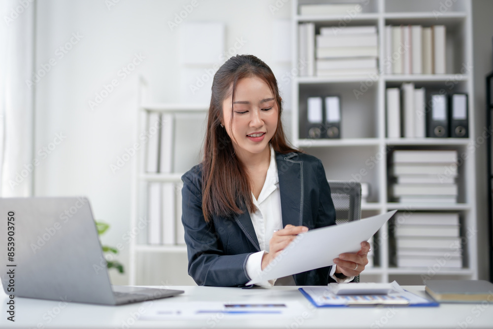 Professional businesswoman working at her desk in a modern office, reviewing documents, and smiling confidently. Professional businesswoman working at her desk in a modern office, reviewing documents, and smiling confidently.