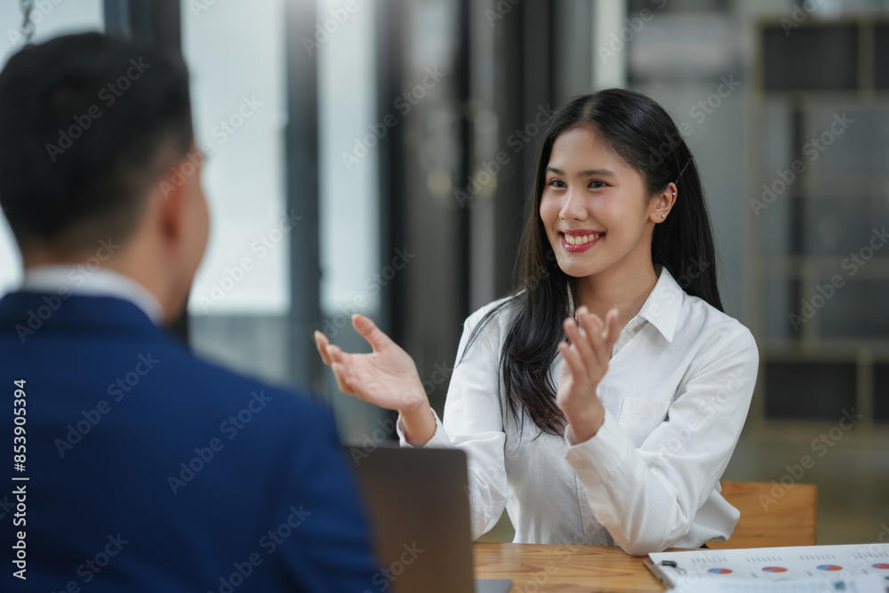 Confident woman clapping hands in business meeting while sitting across from a colleague in office setting, wearing professional attire. Confident woman clapping hands in business meeting while sitting across from a colleague in office setting, wearing professional attire.