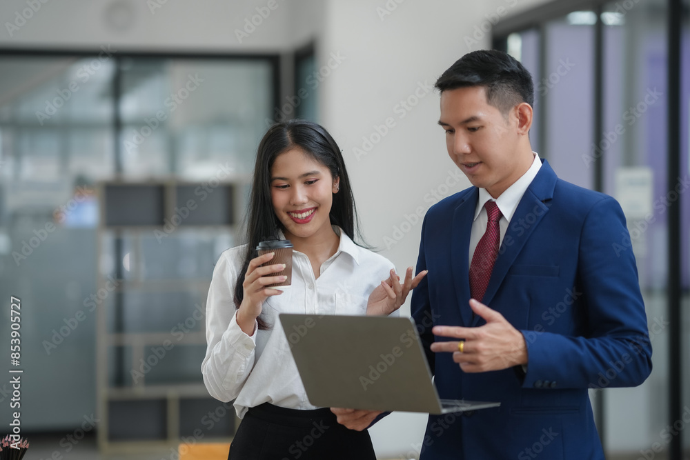 Two business professionals collaborating and discussing a project while looking at a laptop in a modern office environment. Two business professionals collaborating and discussing a project while looking at a laptop in a modern office environment.